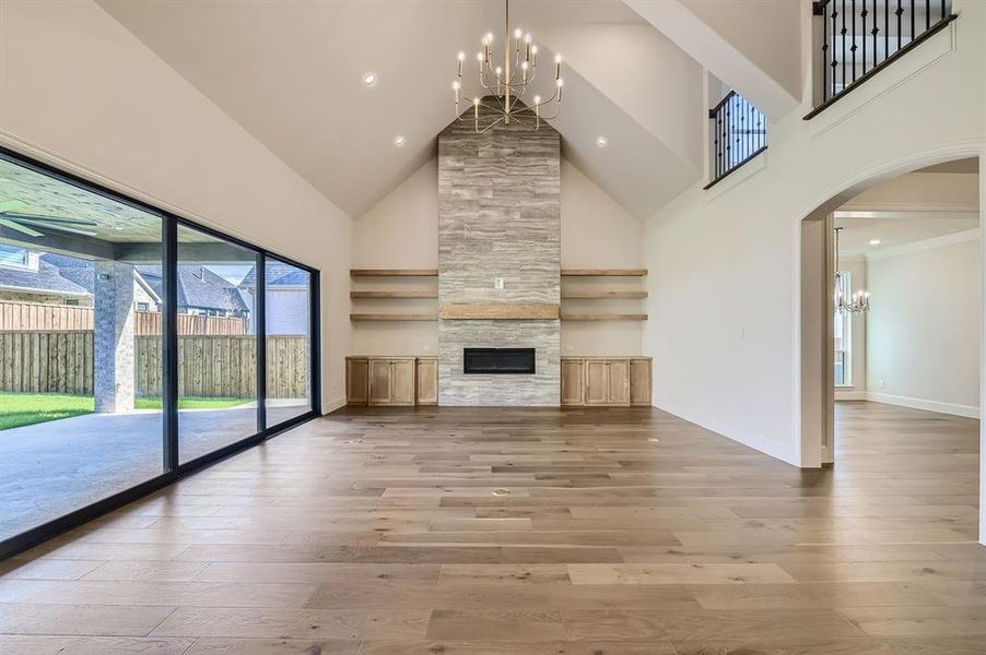 Living room featuring high vaulted ceiling, hardwood / wood-style flooring, and a large fireplace