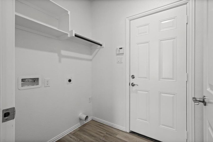 Laundry room with baseboards, laundry area, hookup for a washing machine, electric dryer hookup, and dark wood-style flooring