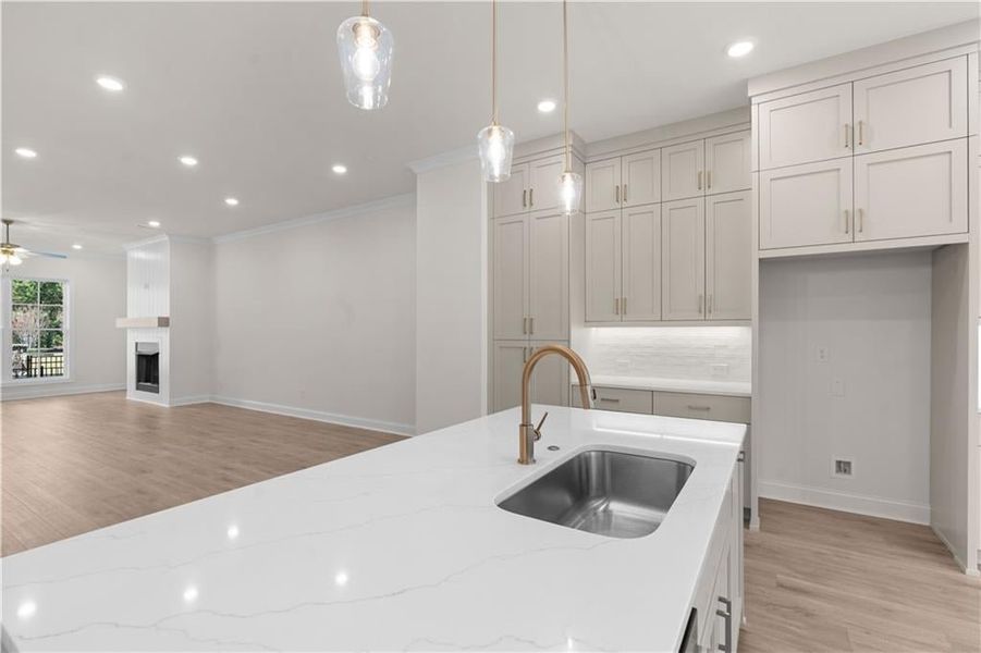 Kitchen with light wood-type flooring, pendant lighting, light stone countertops, recessed lighting, and open floor plan