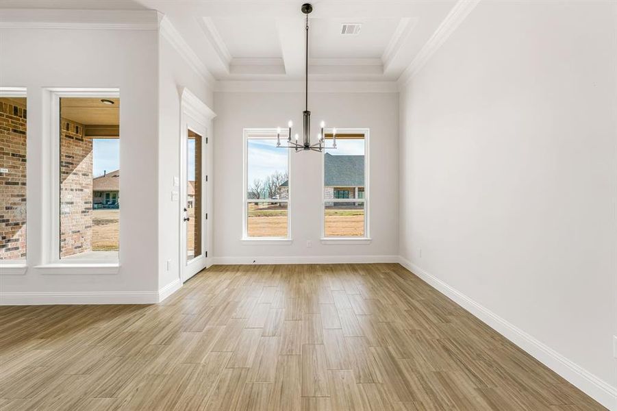 Unfurnished dining area featuring an inviting chandelier, ornamental molding, beam ceiling, and light hardwood / wood-style floors