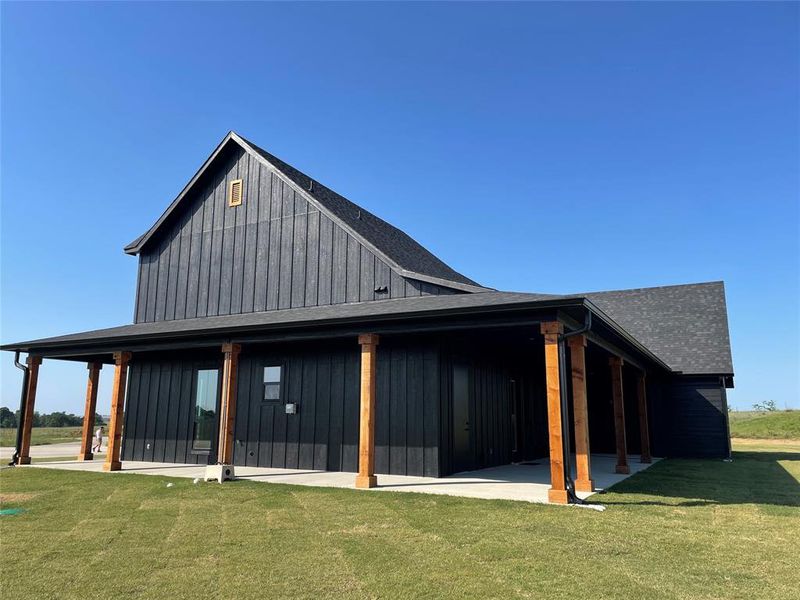 Modern farmhouse-style exterior featuring dark vertical siding and a steeply pitched shingle roof
