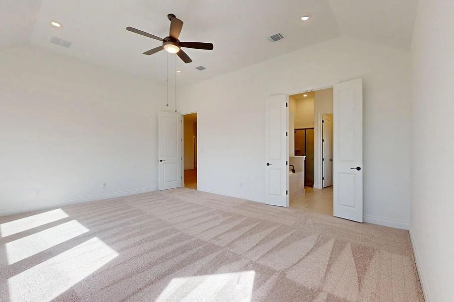 This spacious room features vaulted ceilings, recessed lighting, and a ceiling fan