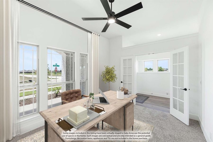 Home office with wood desk, ceiling fan, tall windows, and French doors leading to adjacent room