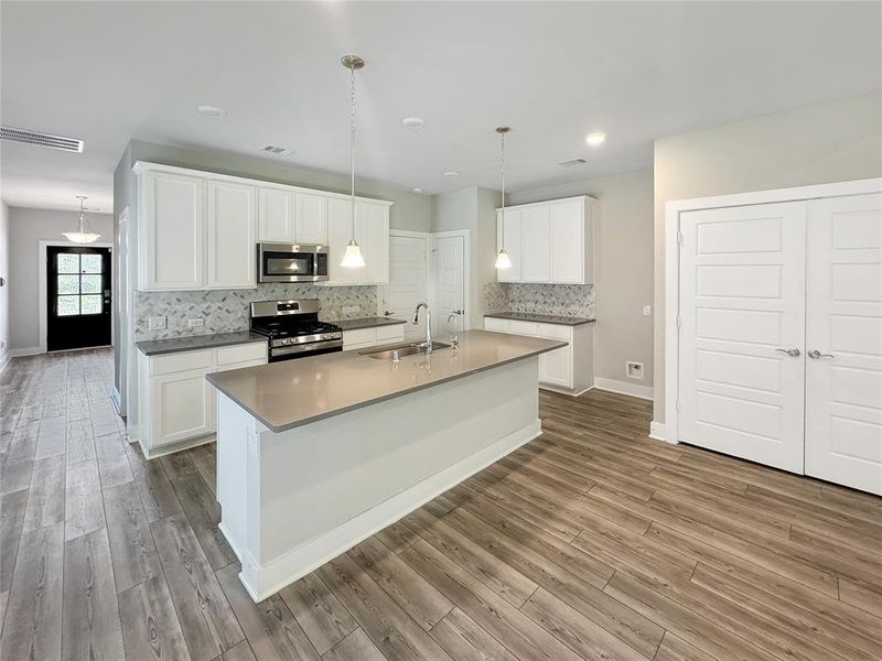 Modern  living space , white walls, ceiling fan, and an open kitchen with island and pendant lights.