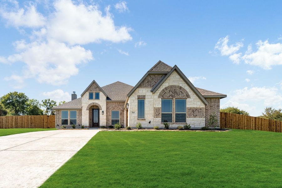 Single-story home with brick and stone exterior, arched entry, large front lawn, and concrete driveway