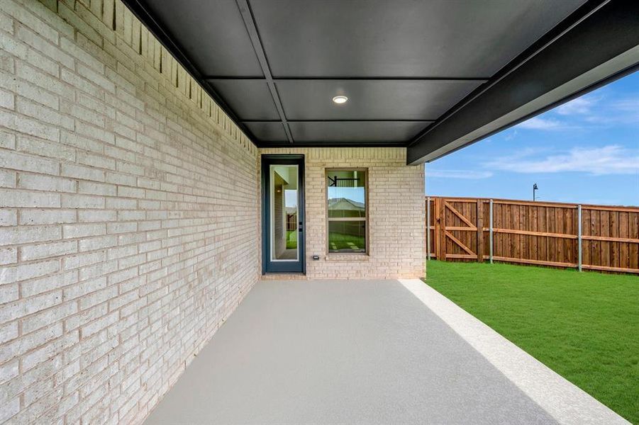 Covered patio featuring a light brick exterior and a dark paneled ceiling