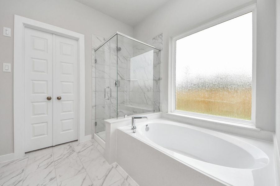 Escape to a spa-like oasis in this primary bathroom. Enjoy a walk-in shower with tile surround, a separate garden tub with custom detailing, and an elegant vanity featuring light countertops, modern hardware, and beautiful recessed lights. Experience luxury and relaxation in every detail. Sample photo of completed home with similar floor plan. Actual colors and selections may vary. Escape to a spa-like oasis in this primary bathroom. Enjoy a walk-in shower with tile surround, a separate garden tub with custom detailing, and an elegant vanity featuring light countertops, modern hardware, and beautiful recessed lights. Experience luxury and relaxation in every detail. Sample photo of completed home with similar floor plan. Actual colors and selections may vary.