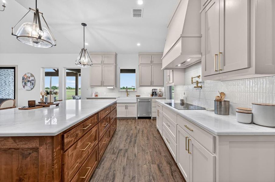 Gourmet kitchen featuring a large central island with wood cabinetry, light-toned perimeter cabinetry, white countertops, wood-finish flooring, and pendant lighting