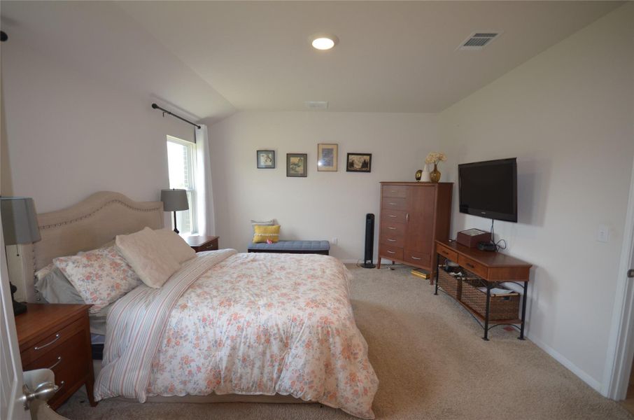 Bedroom featuring light colored carpet and vaulted ceiling Bedroom featuring light colored carpet and vaulted ceiling