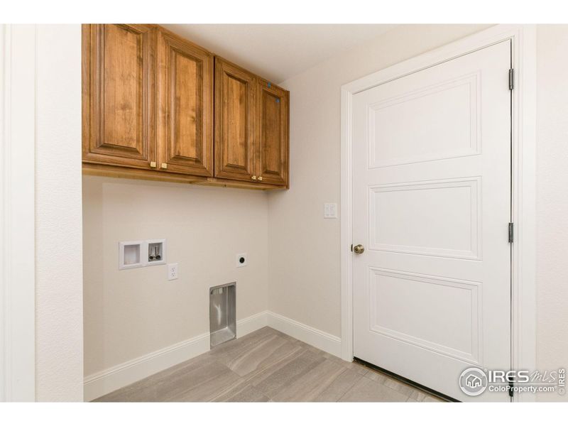 On the other wall of the mudroom is the washer/dryer hookups with overhead cabinets above