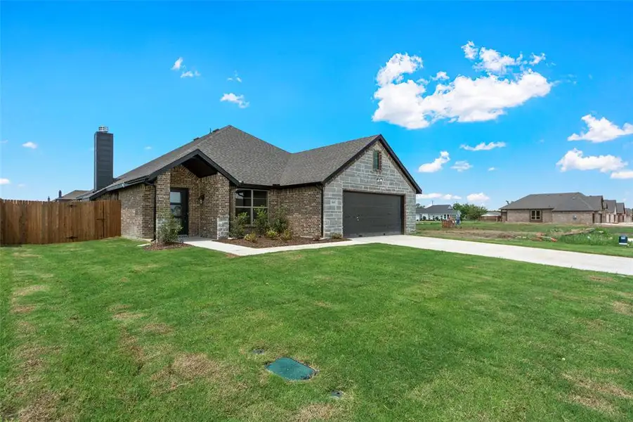 View of front of property featuring a chimney, driveway, brick siding, and an attached garage