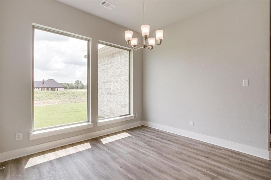 Empty room featuring an inviting chandelier and wood-type flooring