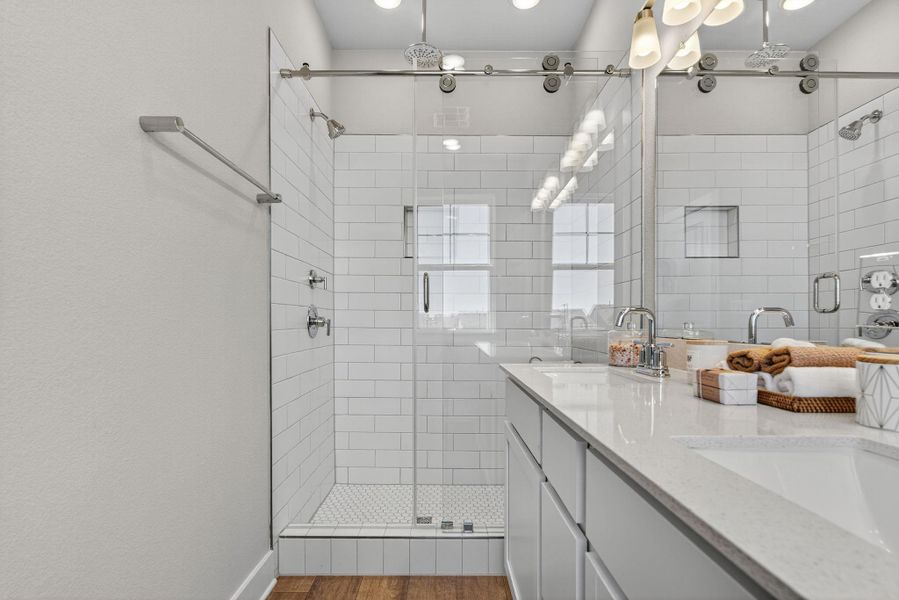 Bathroom featuring double vanity, a stall shower, and wood finished floors
