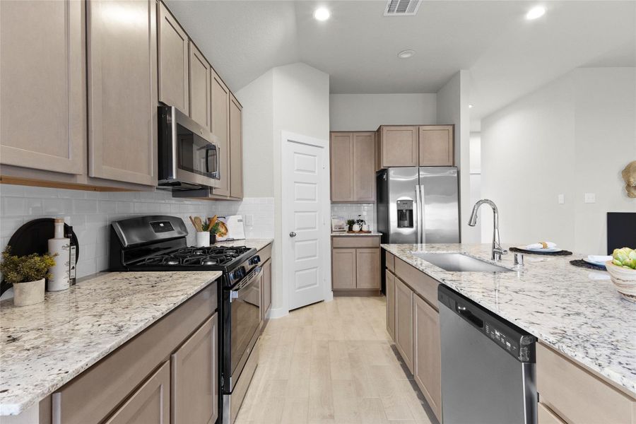 Well-appointed kitchen features granite countertops, abundant cabinetry, stainless steel appliances, a gas range, subway tile backsplash, and a large island with sink. Well-appointed kitchen features granite countertops, abundant cabinetry, stainless steel appliances, a gas range, subway tile backsplash, and a large island with sink.