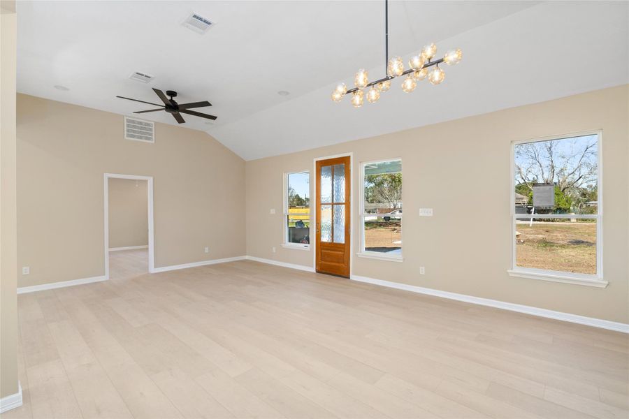 Spacious, open-concept livingroom with vaulted ceilings,expansive windows, and astylish ceiling fan. This wideangle view showcasesseamless flow and room forevery lifestyle.