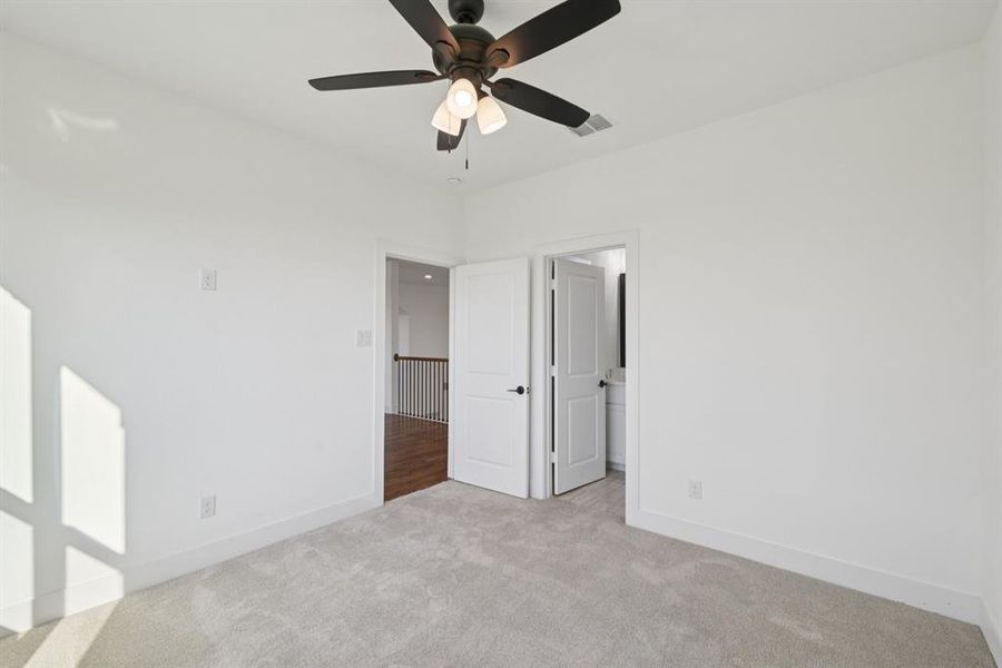 Unfurnished bedroom with light colored carpet and ceiling fan