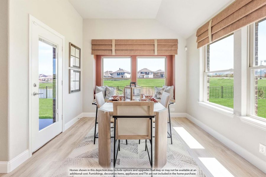 Bright dining area with wood table, built-in bench seating, and large windows overlooking a green backyard