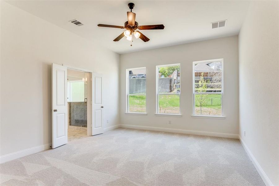 Empty room with ceiling fan and light colored carpet