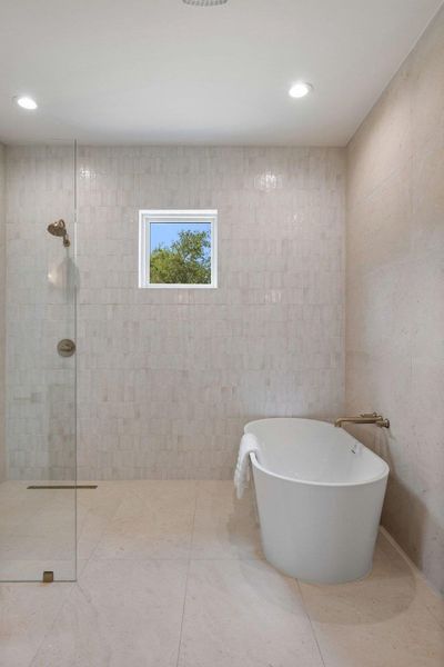 A freestanding soaking tub alongside a sleek glass-enclosed shower creates a spa-like retreat.