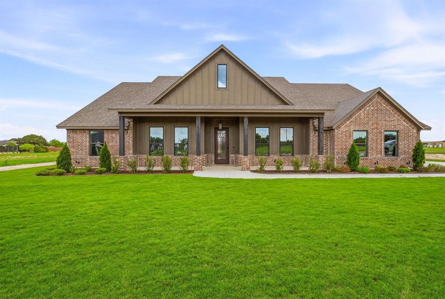 Craftsman house with brick siding, a porch, a front lawn, a shingled roof, and board and batten siding