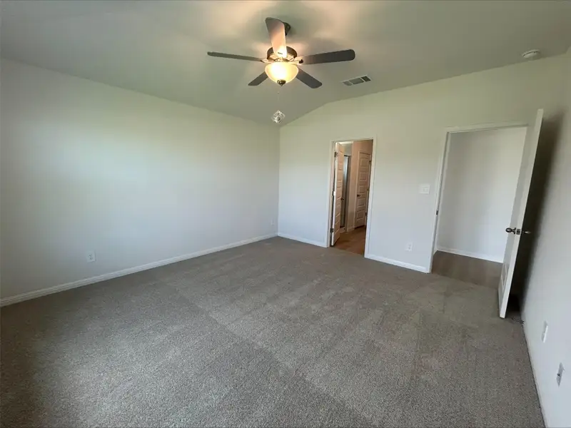 Unfurnished bedroom featuring lofted ceiling, carpet, a ceiling fan, and ensuite bathroom