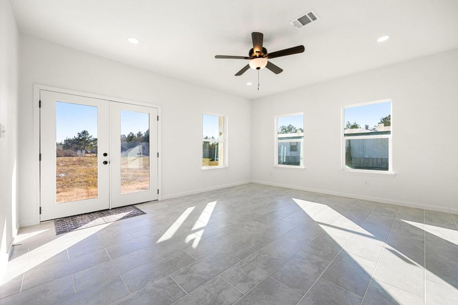 Bright living room with large windows, modern tile flooring, and elegant double doors revealing a scenic view. Bright living room with large windows, modern tile flooring, and elegant double doors revealing a scenic view.