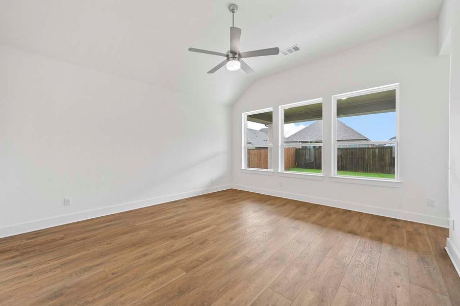 Spare room with baseboards, visible vents, ceiling fan, vaulted ceiling, and wood finished floors