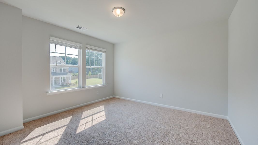 Comfortably sized Ridgewood secondary bedroom with carpet flooring and natural light at Bowers Farm in McDonough, GA.