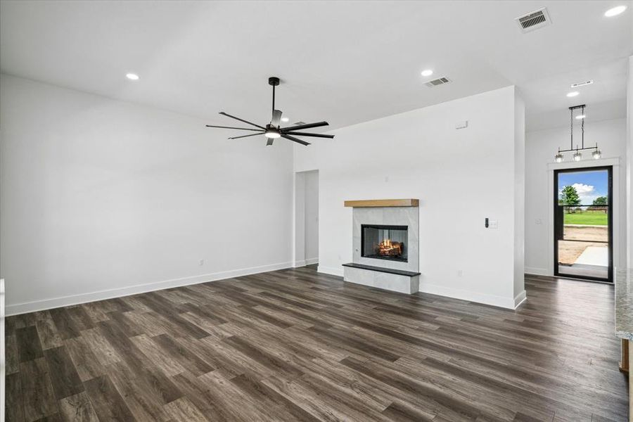 Unfurnished living room with dark wood-style floors, recessed lighting, a tile fireplace, and a ceiling fan