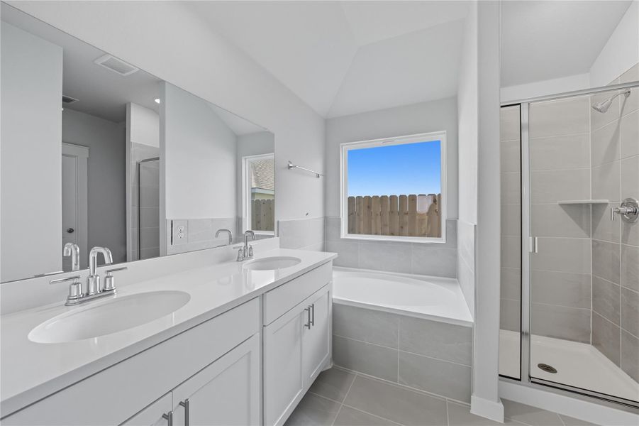 Full bath featuring a bath, a shower stall, double vanity, and light tile patterned flooring Full bath featuring a bath, a shower stall, double vanity, and light tile patterned flooring