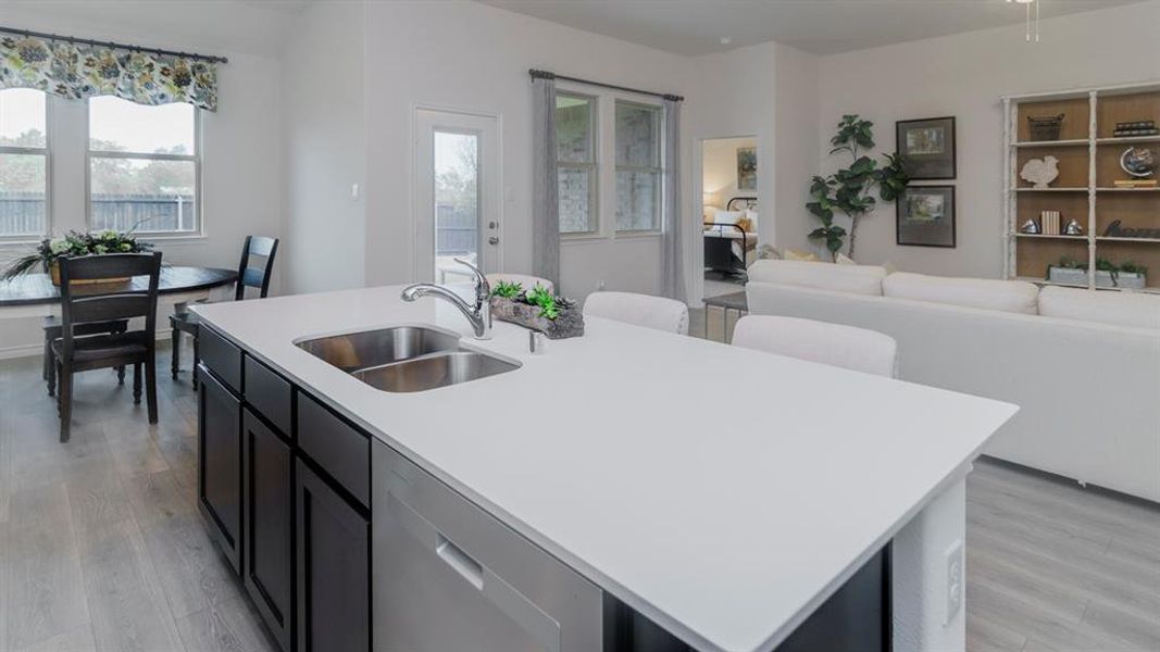 Kitchen island featuring a double-basin stainless steel sink and white solid surface countertop