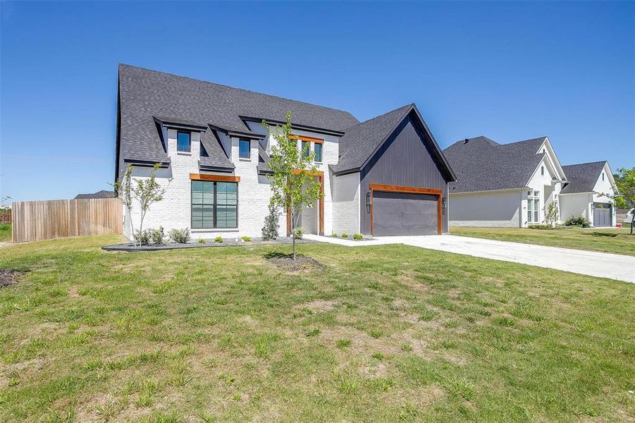 Modern farmhouse style home featuring a garage and a front lawn