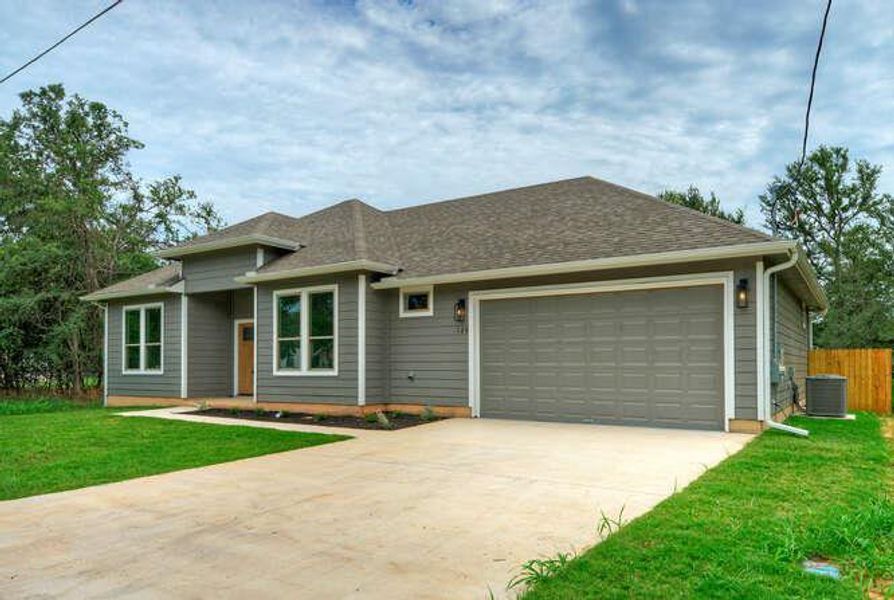 View of front of house with concrete driveway, an attached garage, and a shingled roof