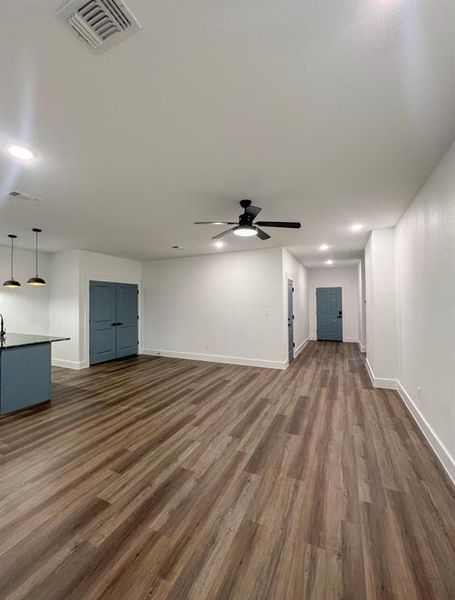 Unfurnished living room featuring ceiling fan and dark hardwood / wood-style flooring