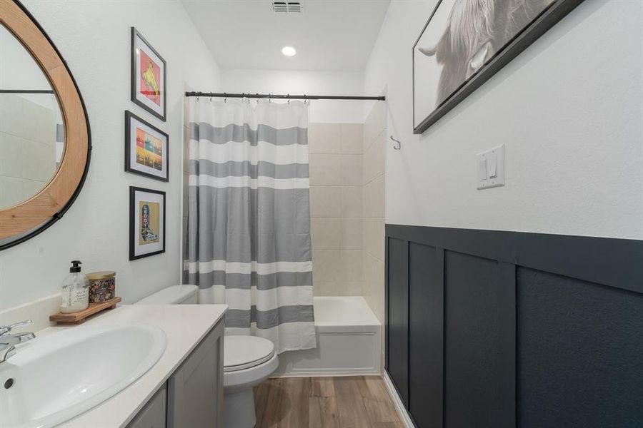 Full bathroom with hardwood / wood-style flooring, vanity, shower / tub combo, and toilet