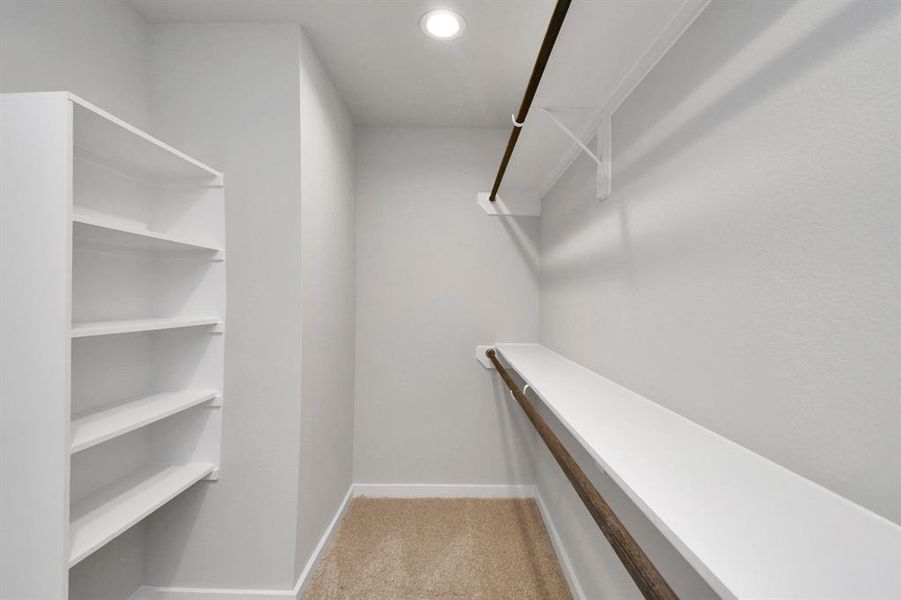 Walk-in closet that epitomizes luxury and practicality. This generously sized space features built-in shelving, offering abundant room for impeccable organization.  Sample photo of completed home with similar floor plan. Actual colors and selections may vary.