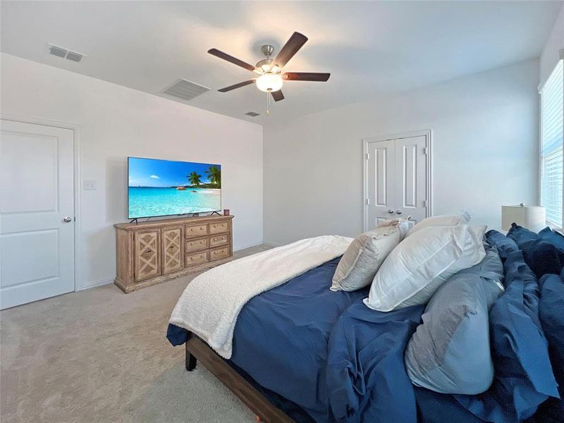 Carpeted bedroom with ceiling fan and a closet