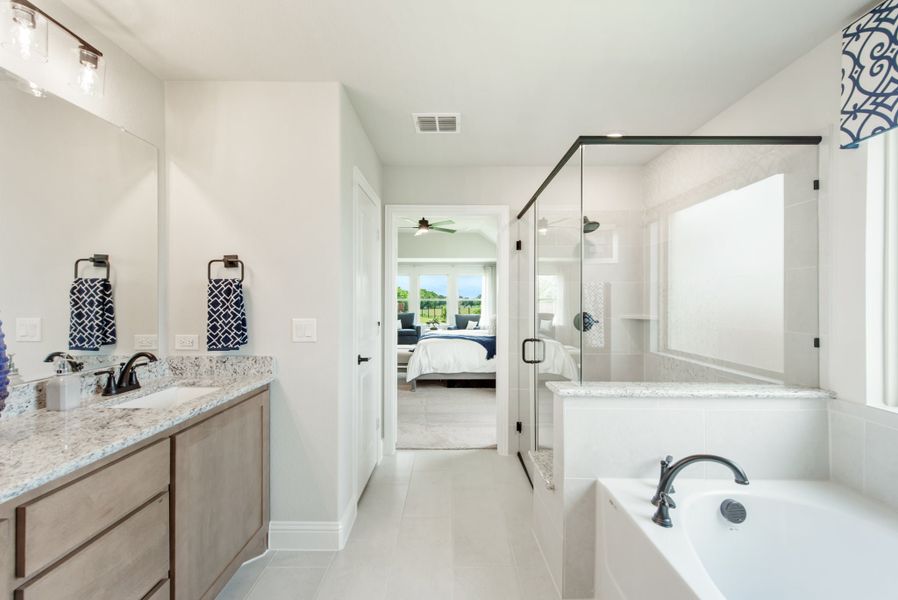 Master bathroom with double vanity, granite countertops, soaking tub, and glass walk-in shower
