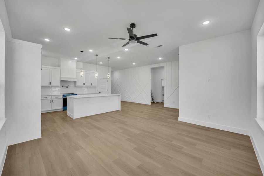 Kitchen featuring electric stove, light hardwood / wood-style floors, white cabinets, a kitchen island, and decorative light fixtures