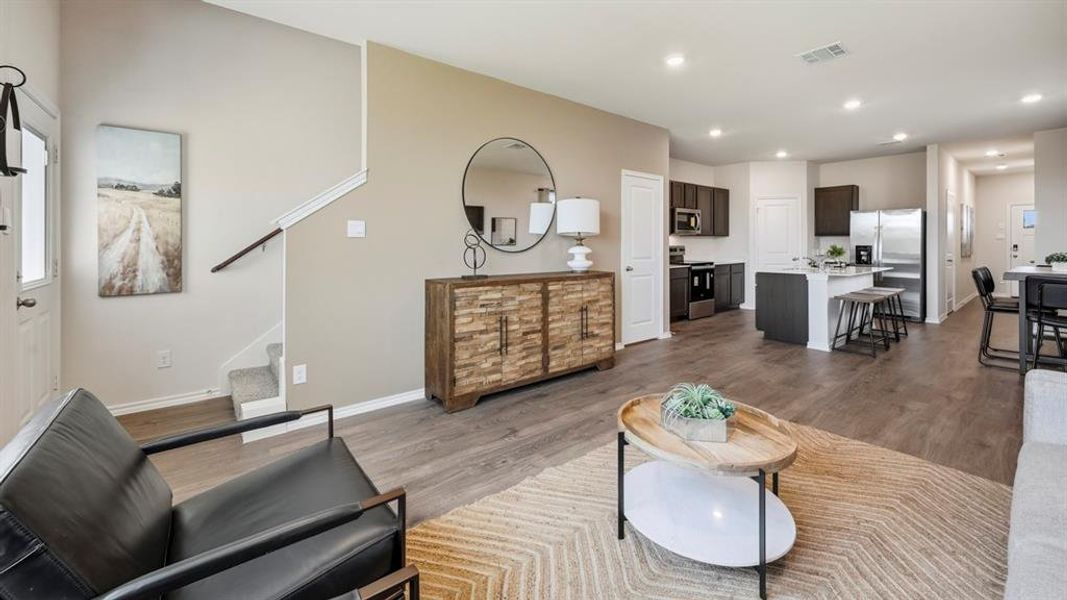 Living room featuring stairway, dark wood-type flooring, recessed lighting, and healthy amount of natural light