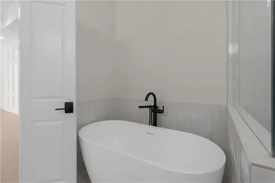a perfect place to begin or end the day in this freestanding soaking tub with floor-mounted filler, white paneled door, and glass-enclosed shower