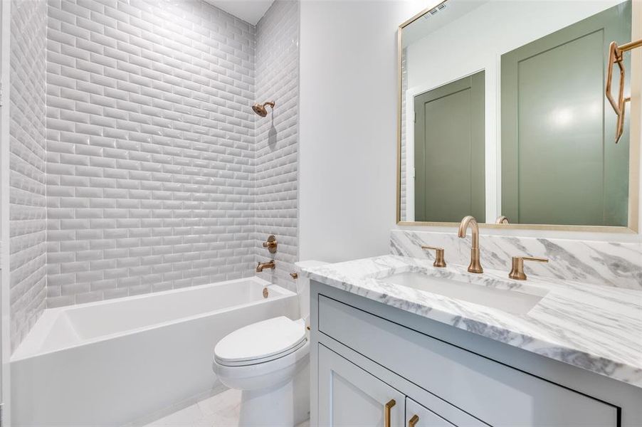 Full bathroom with toilet, tile patterned floors, tiled shower / bath combo, and vanity