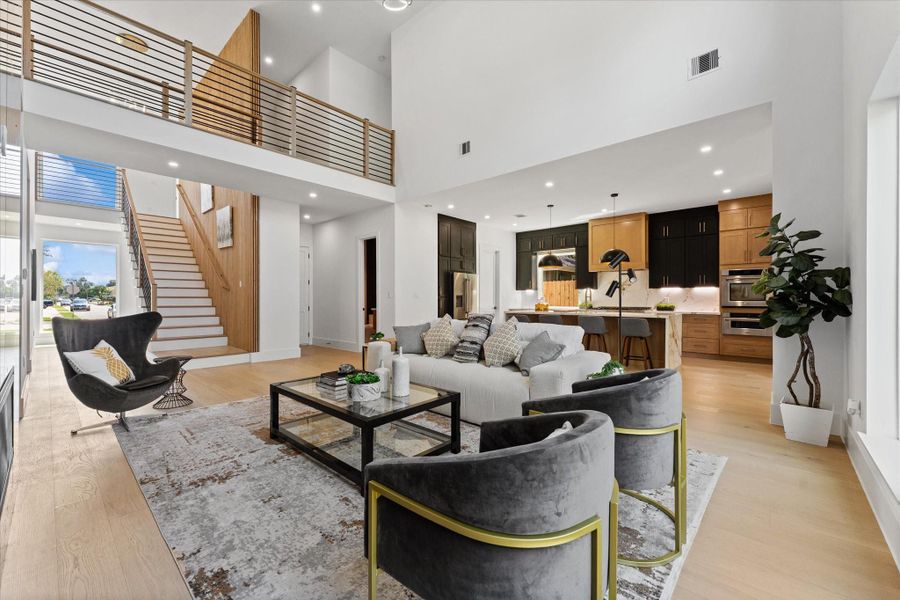 This modern open concept living area features an open design that is ready for you to create your cozy oasis. The kitchen, visible in the background, offers sleek cabinetry, a large island with seating, and modern appliances. Neutral tones and elegant lighting create a warm, inviting atmosphere perfect for entertaining. This modern open concept living area features an open design that is ready for you to create your cozy oasis. The kitchen, visible in the background, offers sleek cabinetry, a large island with seating, and modern appliances. Neutral tones and elegant lighting create a warm, inviting atmosphere perfect for entertaining.