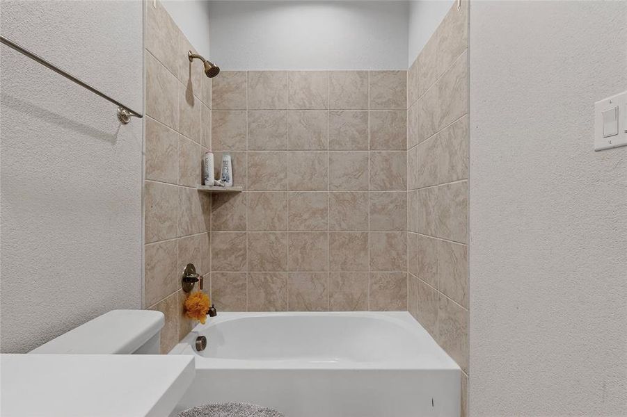 Full bathroom featuring a textured wall and bathing tub / shower combination