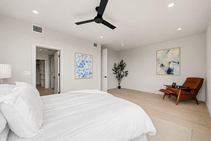 A tranquil primary bedroom suite featuring light wood flooring and a spacious walk-in closet. A tranquil primary bedroom suite featuring light wood flooring and a spacious walk-in closet.