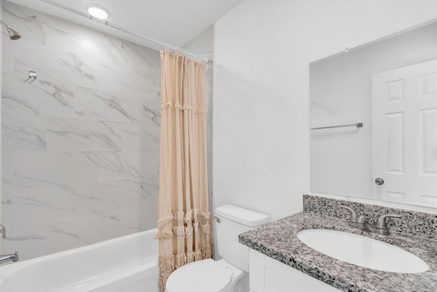 This bathroom features a sleek design with a marble-tile shower, a white bathtub, and a granite countertop on the vanity. It has a soft, neutral color palette and a modern feel. This bathroom features a sleek design with a marble-tile shower, a white bathtub, and a granite countertop on the vanity. It has a soft, neutral color palette and a modern feel.