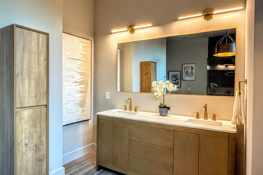 Bathroom with double vanity, wood finished floors, baseboards, and a sink