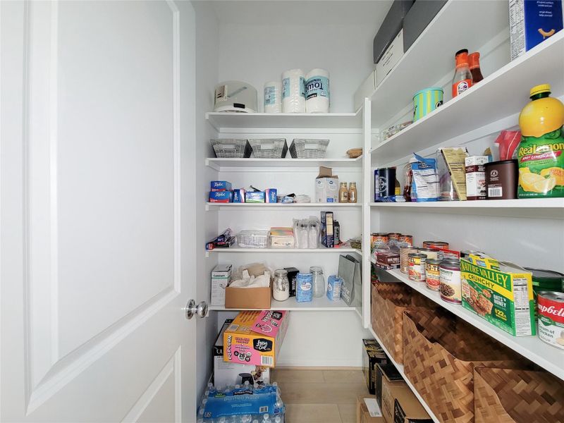 Pantry with white shelves.  It features ample storage space, providing efficient organization for a busy household.