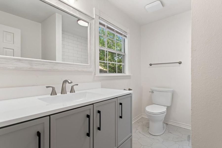 Bathroom with vanity, toilet, tile patterned floors, and baseboards