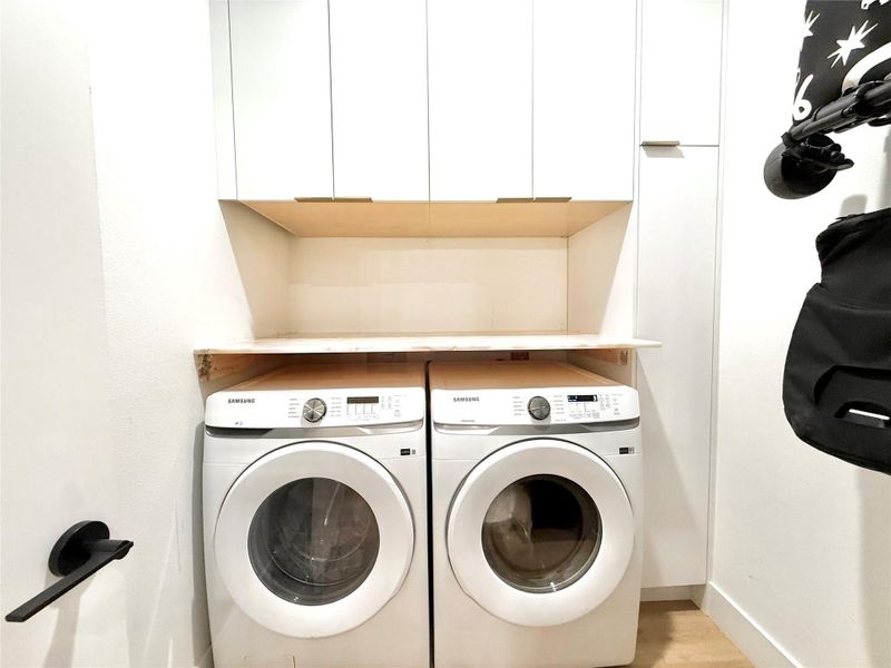 Laundry area with cabinet space, washer and clothes dryer, and wood finished floors